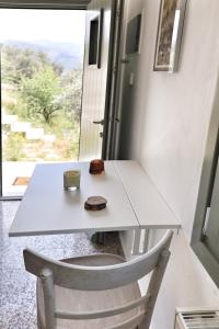 a white table and chair with a cup on it at Little house in the olive grove in Melissátika