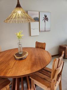 a wooden table with chairs and a vase with a plant on it at Apartamento Super Charmoso Condomínio OAHU Alto do Imbassaí in Imbassai
