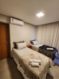 una habitación de hospital con dos camas y toallas. en Apartamento Super Charmoso Condomínio OAHU Alto do Imbassaí en Imbassai