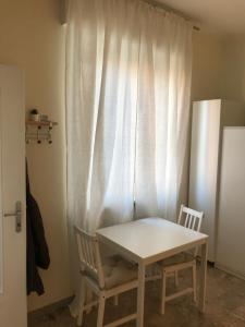 a white table and two chairs in front of a window at Residenza Eli in Piacenza