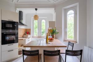 a kitchen with a table with chairs and a kitchen with windows at Petit Manoir en Ville - Golden Tree - Parking privé in Strasbourg