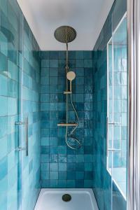 y baño de azulejos azules con bañera y ducha. en Petit Manoir en Ville - Golden Tree - Parking privé en Estrasburgo