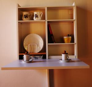 Un estante con dos tazas y un plato. en Bed and Berli, en Sesto Fiorentino