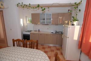 a kitchen with a table and a white refrigerator at Apartments Kraj, Tratica Beach in Kraj