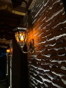 a lamp on a brick wall with a light on it at Bobosh Hotel in Bukhara