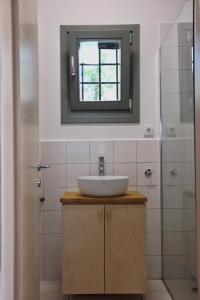 La salle de bains est pourvue d'un lavabo et d'un miroir. dans l'établissement Admonis - Home in the olive grove, à Melissátika