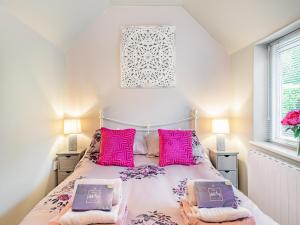 a bedroom with a bed with pink pillows at Pittendrigh Cottage in Briston