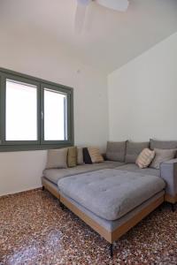 - un grand canapé dans une chambre avec 2 fenêtres dans l'établissement Admonis - Home in the olive grove, à Melissátika