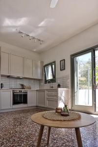 une cuisine avec des placards blancs et une table dans l'établissement Admonis - Home in the olive grove, à Melissátika