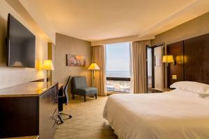パナマシティにあるSheraton Grand Panamaのベッドと大きな窓が備わるホテルルームです。