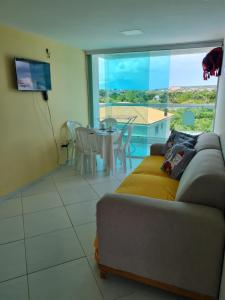 a living room with a couch and a large window at Condomínio mar e sol in Conde