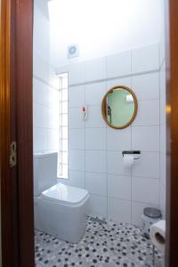 a white bathroom with a toilet and a mirror at Bujtina Sidheri in Korçë