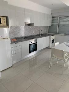cocina con electrodomésticos blancos, mesa, mesa y sillas en Squash Club Apartamentos en Portimão