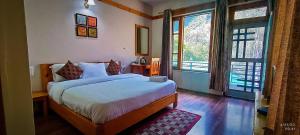 Banjār的住宿－Tirthan Grand Riverside，一间卧室设有一张床和两个大窗户