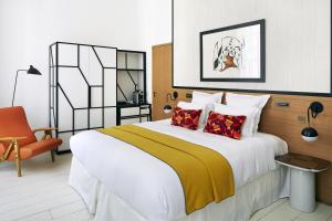 een slaapkamer met een groot bed en een oranje stoel bij Hôtel du Ministère in Parijs