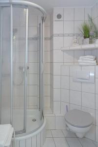 La salle de bains blanche est pourvue d'une douche et de toilettes. dans l'établissement Ad5 409 Monis Beachhouse, à Westerland