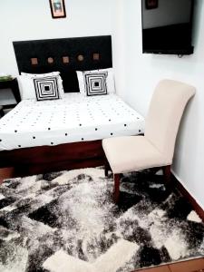 sypialnia z białym łóżkiem i krzesłem w obiekcie RB studio apartment with free Wi-Fi w mieście Dar es Salaam
