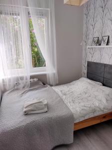 a bedroom with a bed with white sheets and a window at Apartament Centrum Śródmieście in Olsztyn