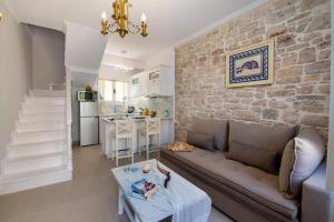 a living room with a couch and a stone wall at Evi's Maisonette in Longós