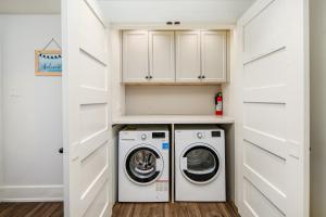a laundry room with white cabinets and a washer and dryer at Gorgeous 4-Bedroom Garden Level Suite at Vancouver West in Vancouver