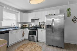 a kitchen with white cabinets and a stainless steel refrigerator at Boho Inspired Apt in the heart of Tampa Bay! in Tampa