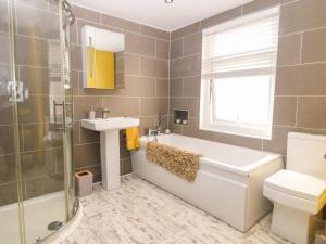 a bathroom with a tub and a sink and a toilet at Apartment 1 - Llandudno Central in Llandudno +27 photos