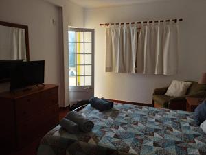 a bedroom with a bed and a dresser and a television at Costa do Moinho in Longueira