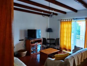 uma sala de estar com um sofá e uma televisão em Costa do Moinho em Longueira