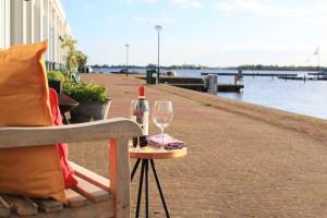 uma garrafa de vinho e um copo num banco em The Comfort of a Luxury Hotel, but with your own fully equipped Kitchen em Loosdrecht
