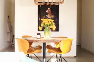 una mesa de comedor con sillas amarillas y un jarrón de flores en The Comfort of a Luxury Hotel, but with your own fully equipped Kitchen, en Loosdrecht