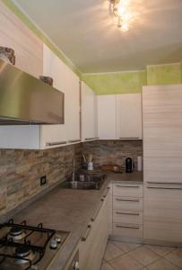a kitchen with white cabinets and a sink at *[Stella Alpina]*accogliente casa, giardini, wi-fi in Borgo Lares