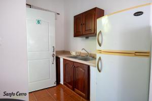 a kitchen with a white refrigerator and a sink at Hotel Santo Cerro Natural Park in Santo Cerro