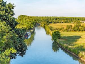 a river with a boat in the middle at Southfield Workshop in Braunston