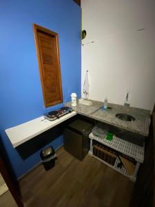 La salle de bains est pourvue d'un lavabo et d'un mur bleu. dans l'établissement Kitnet aconchegante próximo à Praia do Forte, à Mata de São João