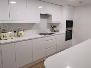 a white kitchen with white cabinets and a sink at SeaSky in Portland