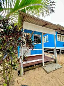 a blue house with a porch on the beach at Khafii Village in Kampong Pasir Panjang