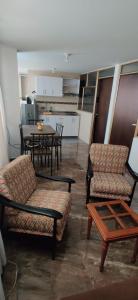 a living room with chairs and a table and a kitchen at Que chimba de apto. in Bogotá