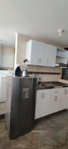 a kitchen with white cabinets and a black refrigerator at Que chimba de apto. in Bogotá