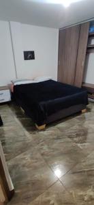 a bedroom with a bed with a black blanket on the floor at Que chimba de apto. in Bogotá
