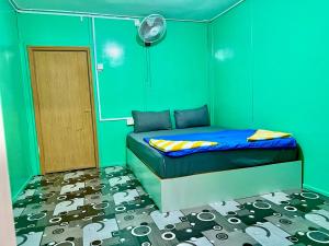 ein Schlafzimmer mit einem Bett mit grünen Wänden und einer Tür in der Unterkunft Khafii Village in Kampong Pasir Panjang