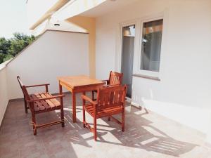 a porch with a table and two chairs and a window at Apartments Nikola Caska in Novalja