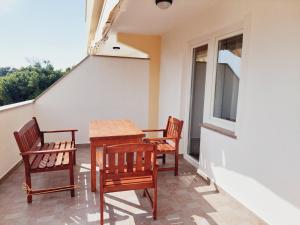 a table and chairs on a balcony with a window at Apartments Nikola Caska in Novalja