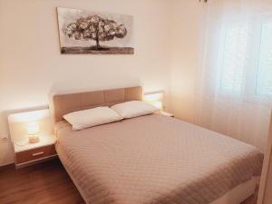 a bedroom with a bed with a tree on the wall at Apartments Nikola Caska in Novalja