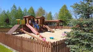un parque infantil con un equipo de juegos en la arena en Domki Romka en Mikołajki