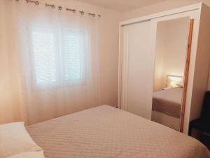 a small bedroom with a bed and a mirror at Apartments Nikola Caska in Novalja