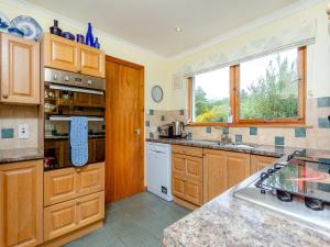 a large kitchen with wooden cabinets and a window at Riverfoot in Glenelg