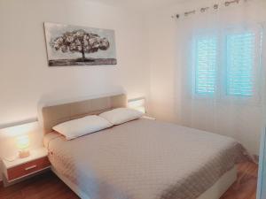 a bedroom with a bed and a tree on the wall at Apartments Nikola Caska in Novalja