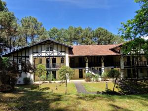 uma casa grande com um telhado de gambrel em Appartements au coeur du golf, proche du lac et vélodyssée em Biscarrosse