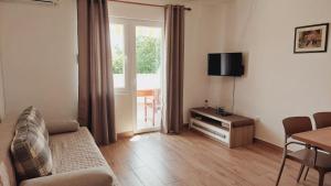 a living room with a couch and a table and a television at Apartments Nikola Caska in Novalja