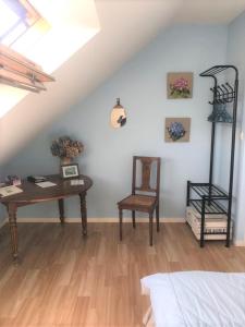 Cette chambre mansardée comprend un bureau et une chaise. dans l'établissement Dom & ses chambres d'hôtes, à Plouigneau